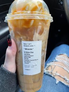 a person holding up a plastic cup filled with liquid and ice cream in their hand