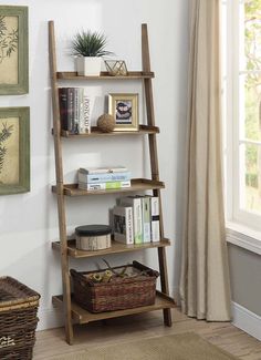 a wooden ladder shelf with books and other items on it next to a window in a living room