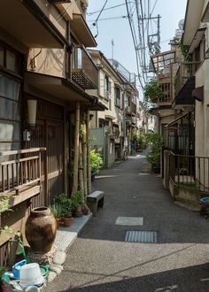 an image of a narrow street with buildings and plants on the side walk in front of it