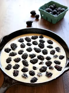 a pan filled with berries and cream on top of a wooden table