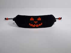 a black beaded bracelet with an orange pumpkin face on it's front and back ends