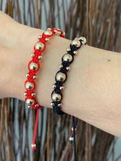 a person wearing two different bracelets on their arm, one with silver beads and the other red string