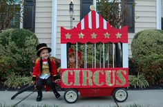 two children dressed up as circus performers in front of a carnival tent with the word circus written on it