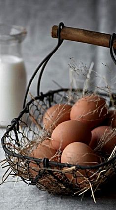 a basket filled with brown eggs next to a bottle of milk on top of a table