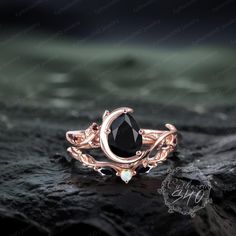 a rose gold ring with an oval black diamond in the center and leaves around it