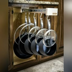 pots and pans are hanging from the wall in a kitchen cabinet with wooden cabinets