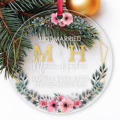 a personalized ornament with flowers and greenery on it, hanging from a christmas tree