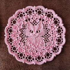 a crocheted doily with a bird on it sitting on a brown surface