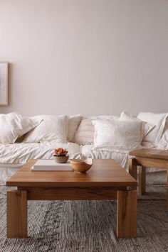 a living room filled with white couches and wooden tables in front of a wall