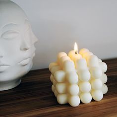 a candle that is sitting next to a white head on top of a wooden table