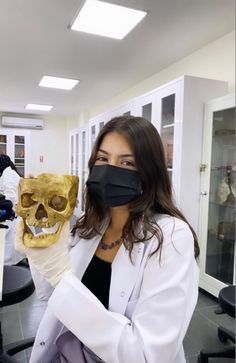 a woman in a lab holding up a skull mask