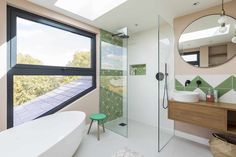 a bathroom with a sink, mirror and bathtub next to a window that looks out onto the outdoors