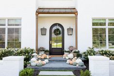 a white house with pumpkins on the front steps