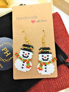 a pair of snowman beaded earrings on top of a card next to a bag