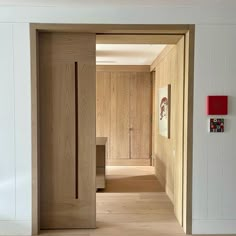 an open door leading into a room with wood paneling and paintings on the walls