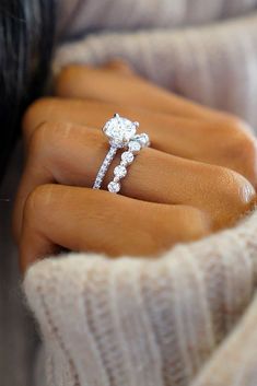 a woman's hand with a diamond ring on top of her finger and an engagement band