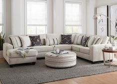 a living room filled with lots of furniture next to two windows and a rug on the floor