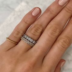 a woman's hand with three different rings on her fingers and one ring in the middle