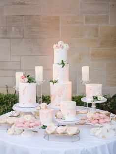 a table topped with lots of white and pink cakes