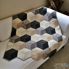 a white chair with a black and grey patchwork quilt on it's back