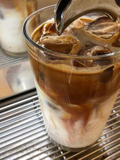 iced coffee being poured into a glass on top of a cooling rack with ice cubes