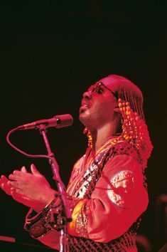 a man standing in front of a microphone on top of a stage with his hands out