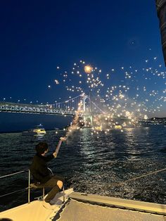 a person sitting on a boat watching fireworks go off in the sky