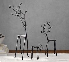 three metal deer sculptures sitting on top of a white floor next to a pile of books