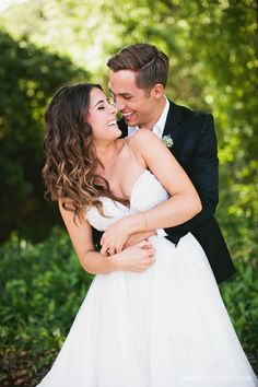 a bride and groom embracing each other in front of trees