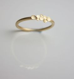 a gold ring with three small dots on it's side, sitting on a white surface