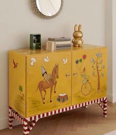 a yellow cabinet with an image of a horse and rider painted on the sideboard