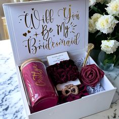 a white box filled with assorted items on top of a marble table next to flowers