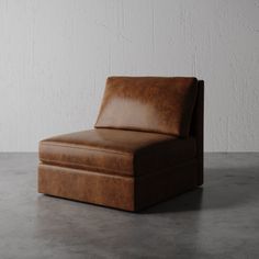 a brown leather chair sitting on top of a cement floor next to a white wall