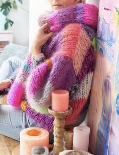 a woman sitting on the floor wearing a colorful sweater