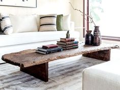 a coffee table with books on it in front of a white couch and window sill