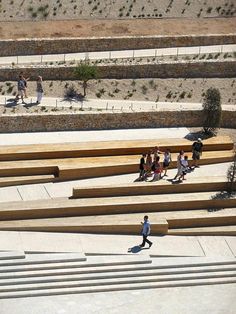 people walking around in the middle of an open area with stairs and benches on it