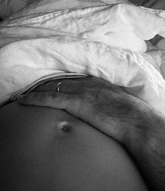 a black and white photo of a pregnant woman's stomach with her hand on the belly