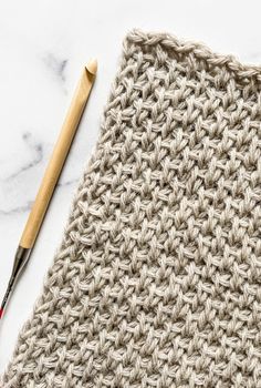 the crochet pattern is next to a knitting needle and a piece of yarn