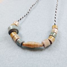 a necklace made out of wood and glass beads on a string with a beaded cord