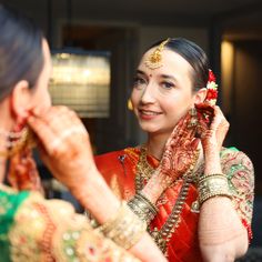 a woman is getting ready to go on her wedding day with the help of another woman