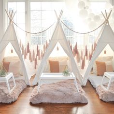 three teepee tents sitting on top of a wooden floor in front of a window