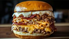 a large cheeseburger with meat and sauce on it's bun is sitting on a wooden table