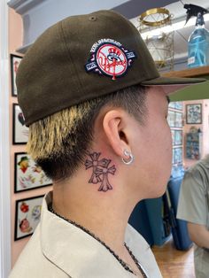 a man with a tattoo on his neck wearing a baseball cap and ear piercings