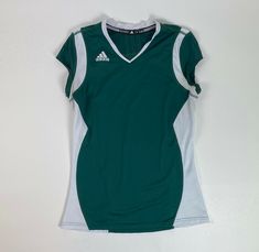 a women's green and white shirt hanging on a wall