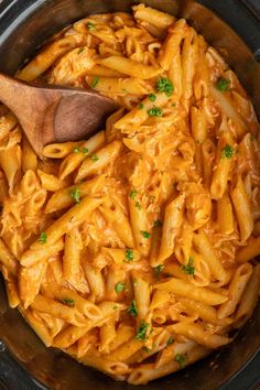 a wooden spoon in a crock pot filled with macaroni and cheese pasta