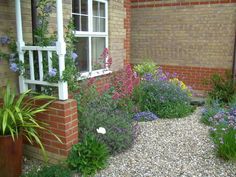 a brick house with lots of flowers in the front yard