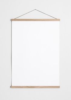 a white board hanging on a wall with a wooden frame and string attached to it