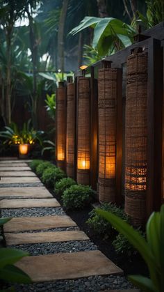 some lights are lit up in the middle of a path between plants and rocks on either side