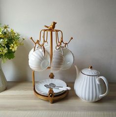 there is a tea set on the table next to a vase with flowers in it