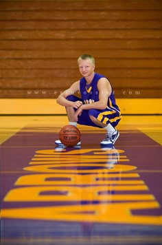 a young man sitting on top of a basketball court next to a basket ball in front of him